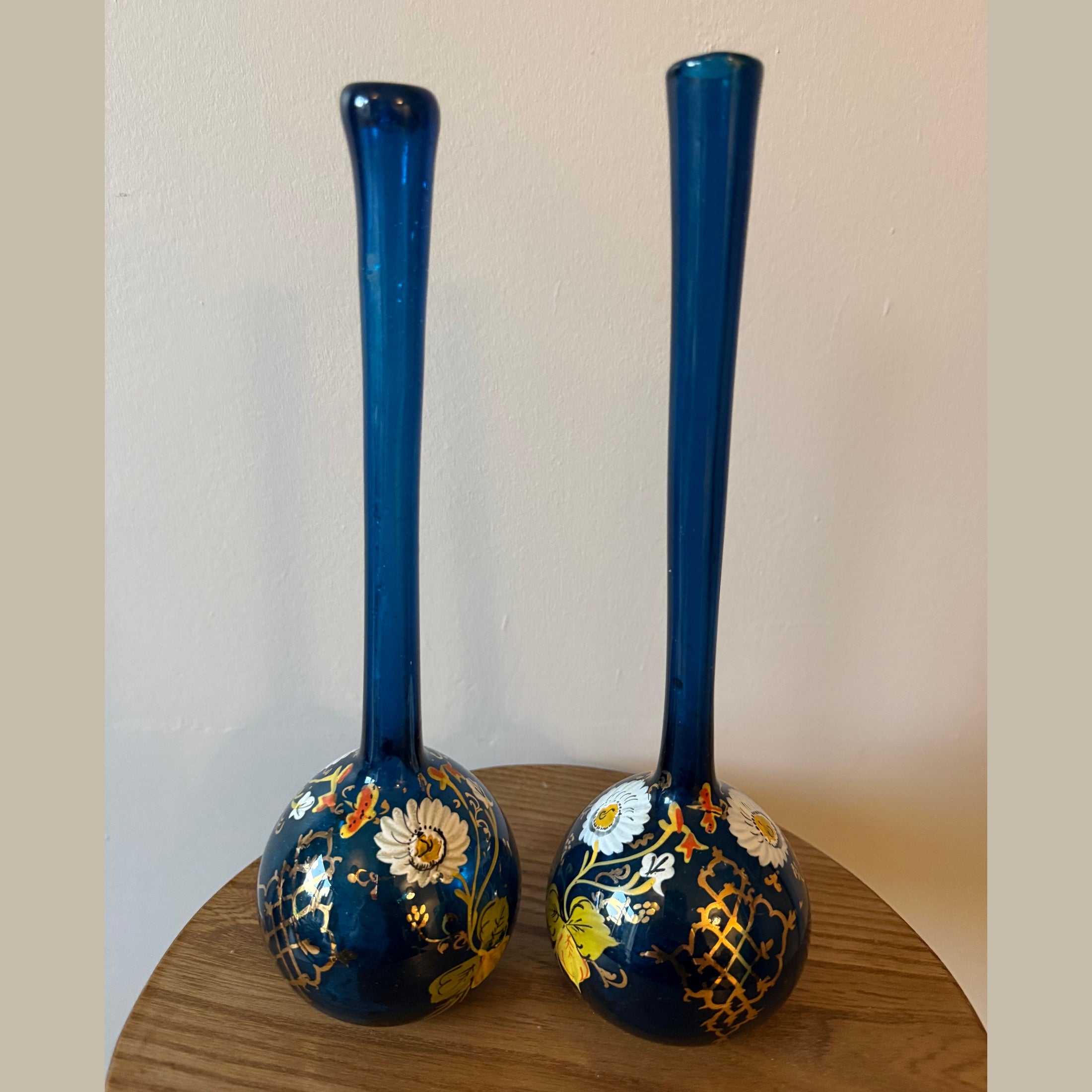 Pair of hand blown blue glass 19th century Persian rose water sprinklers/ bud vases, hand painted enamelled flower and gilt decoration. Measures 29.5cm tall.
